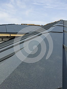 close up view of scaffolding and house under construction with grey folding roof on waterproofing layer