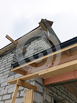 close up view of scaffolding and house under construction with grey folding roof on waterproofing layer