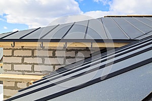 close up view of scaffolding and house under construction with grey folding roof on waterproofing layer