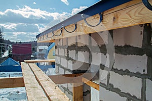 close up view of scaffolding and house under construction with holders for gutters installation