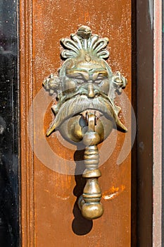 Close up view of a scary looking antique door handle with a human face