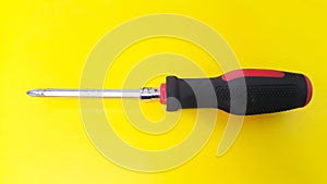 Close up of screwdriver with black and red handle isolated on yellow background