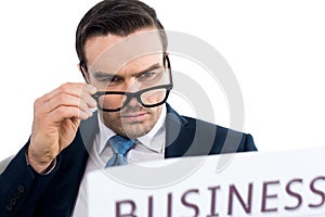 close-up view of serious businessman reading newspaper and adjusting eyeglasses