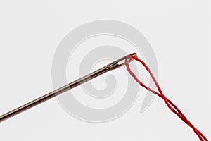 close up view of sewing needle eye and red thread