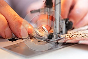 A close-up view of sewing process, hand of old woman using sewing machine, selective focus technique