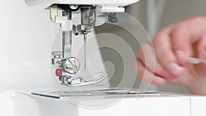 Close up view of sewing process. Spool of thread on working part of sewing machine. Clothing repair.