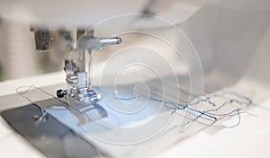 Close up view of sewing process. The stitching white fabric on professional manufacturing machine at workplace
