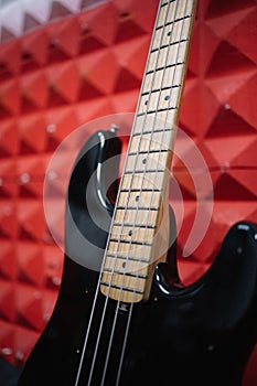 Close-up view of shiny guitar against red wall