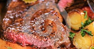 Close up view of a sirloin steak with potatoes and roasted tomatoes