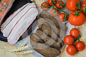 Close-up view of slices of pink bacon, pieces of rye bread, ripe red tomatoes. Fresh organic Food. Quick tasty snack