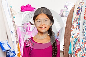 Close-up view of small Asian girl between clothes