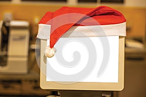 Close up view of small white mockup image blank board with red Santa hat over top.