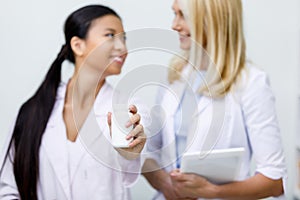 close-up view of smiling female pharmacists holding container