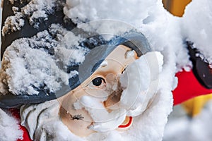 Close-up view of snow-covered gnome face for outdoor decoration at entrance of house on frosty winter day.