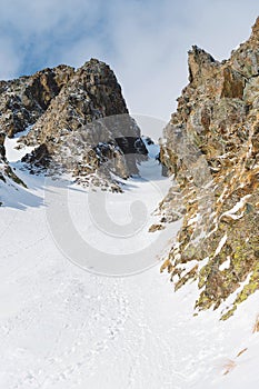 Close-up. View of a snowy couloir between sharp rocks.