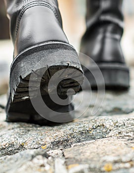Close up view sole black leather boot on stone nature background