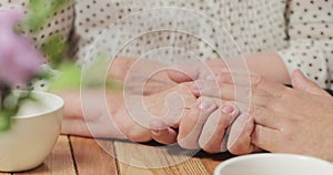 Close up view of sons hands stroking her mothers hands tenderly. Son and mother spending time together indoors. Concept