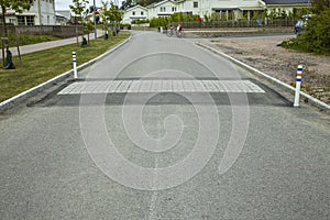 Close up view of speed bump on village street road. Landscape view background.