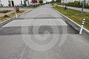 Close up view of speed bump on village street road. Landscape view background. Europe.