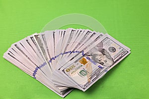 Close up view of spread out stack of dollars isolated on green background