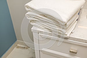 Close-up view of stack of towels on white nightstand in hotel bathroom
