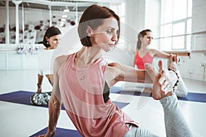 Close up view strong adult woman practicing yoga poses for maintaining health care. Group of active people doing fithess stretchin