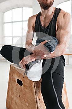 Close up view on strong male athlete resting on wooden box after cross intense in workout gym