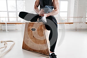 Close up view on strong male athlete resting on wooden box after cross intense in workout gym