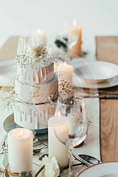 close up view of stylish table setting with candles and wedding cake