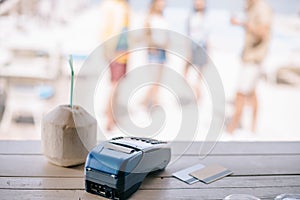 close-up view of summer cocktail with drinking straw and payment terminal with credit cards on bar counter