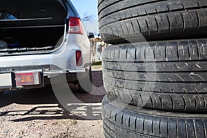 Close up view of summer tire with open trunk of passenger car, seasonal wheel change