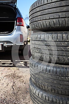 Close up view of summer tyre with open trunk of passenger car, seasonal wheel change