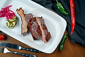 Close up view on tasty delicious bbq coocked ribs with barbecue sauce in white plate on wooden background. Classical american