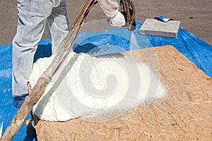 Close up view of technician dressed in a protective white uniform spraying foam insulation using Plural Component Spray Gun.