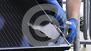 Close-up view of a technician\'s hands installing a solar panel on the roof of a house