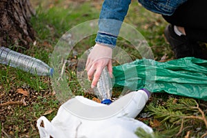 Close up view of a teenage girl hand collecting plastic on the forest. Sustainability concept