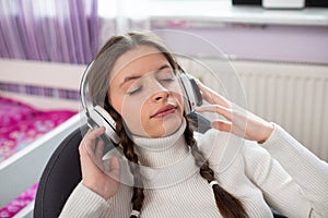 Close-up view of a teenage girl with her eyes closed while listening to music on headphones.