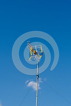 Close up view of a television antenna on a roof over a blue sky