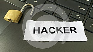 Close up view of text on torn paper - Hacker. With blurred locker and laptop background. Password concept
