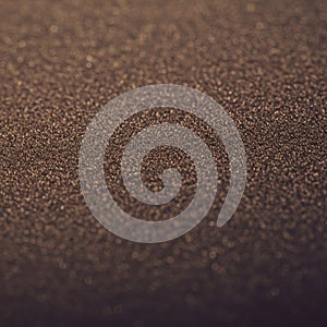 A close-up view of a textured surface resembling fine sand or grains. The surface