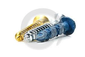 Close up view of three different wood screws in gold, blue and silver colors on white background