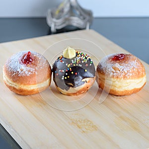 Close up view of three tasty various donuts on wood background. Hanukkah celebration concept.