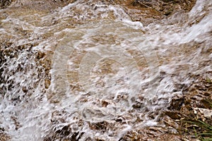 Close-up view to pure water flowing on rocks in mountains.