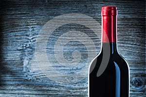 Close up view on top of bottle with red wine on vintage wood