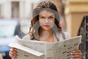 Close up view of tourist girl holding newspaper in her hands.