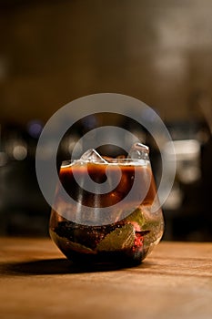 Close-up view of transparent bowl with coffee and herbal drink and ice cubes