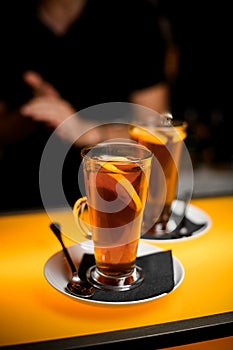 Close-up view of transparent cups on saucer with tea and lemon on bar counter