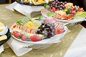 Close up view of tray with various fruits like apples, coconut, oranges, grape, watermelon, plums on the serving table for the