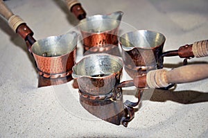 Close up view of turkish coffee prepared on hot golden sand.