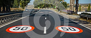 Close-up view of two 50 km per hour, speed limit signs painted on asphalting road. Panoramic banner view.